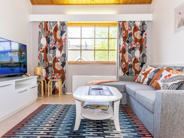 Una sala de estar moderna con televisor, sofá, una mesa de centro y cortinas estampadas.