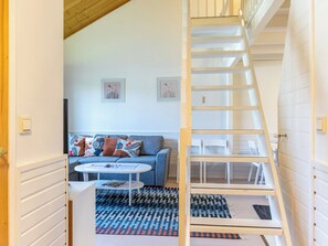 A modern living room with a blue sofa, a white coffee table, and a wooden staircase. - Teerenpesue g 61 by Interhome (Inari)