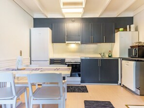 A compact kitchen with a dining area, featuring a refrigerator, stove, microwave, and dishwasher.