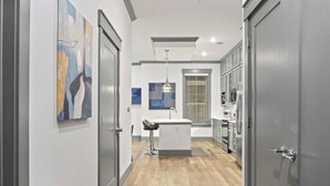 Une cuisine moderne dotée d’un îlot central, de tabourets de bar et d’un luminaire suspendu.
