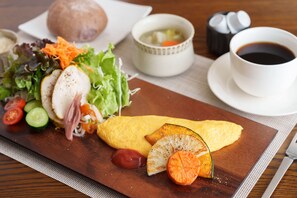 A meal with an omelette, salad, and a bowl of soup on a wooden table. - Lodge Kent (Hokuto)