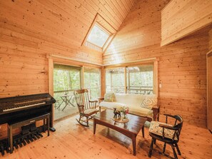 A cozy cabin interior with a piano, seating area, and large windows. - Lodge Kent (Hokuto)