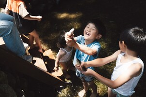 A wooden deck with people standing around, some holding fish.