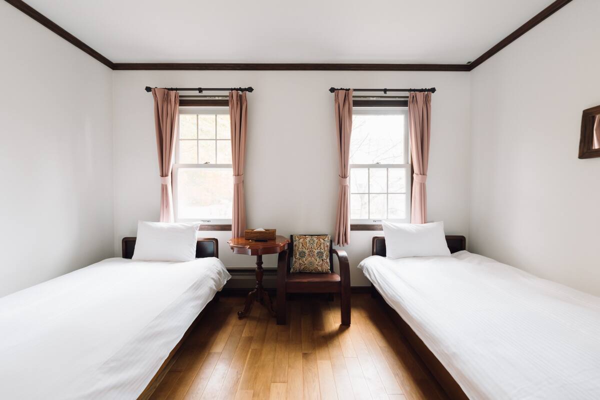 A room with two single beds, a wooden table, and two chairs.