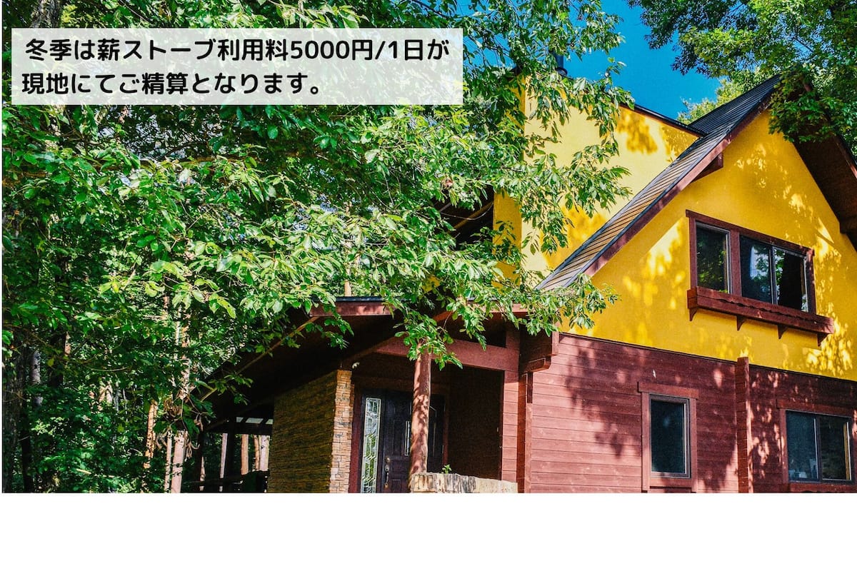A two-story house with a yellow and brown exterior, surrounded by trees.