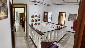 Un pasillo con una escalera de madera, barandilla blanca y detalles decorativos en la pared.