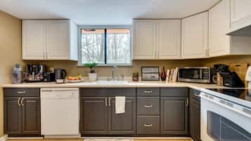 Una cocina moderna con lavavajillas, estufa, microondas y una ventana sobre el fregadero.