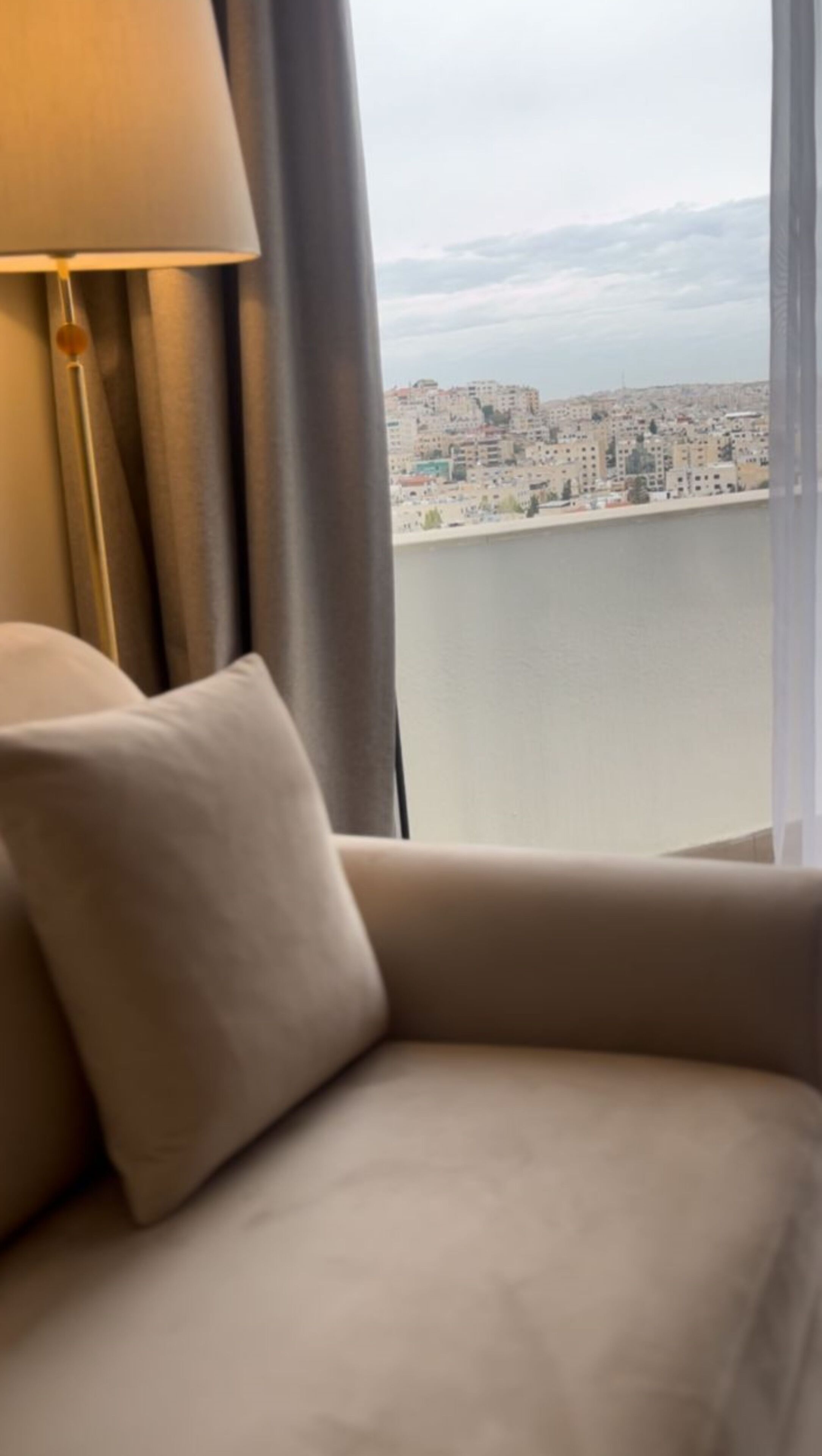 Quarto com vista para a paisagem urbana através de uma janela grande.