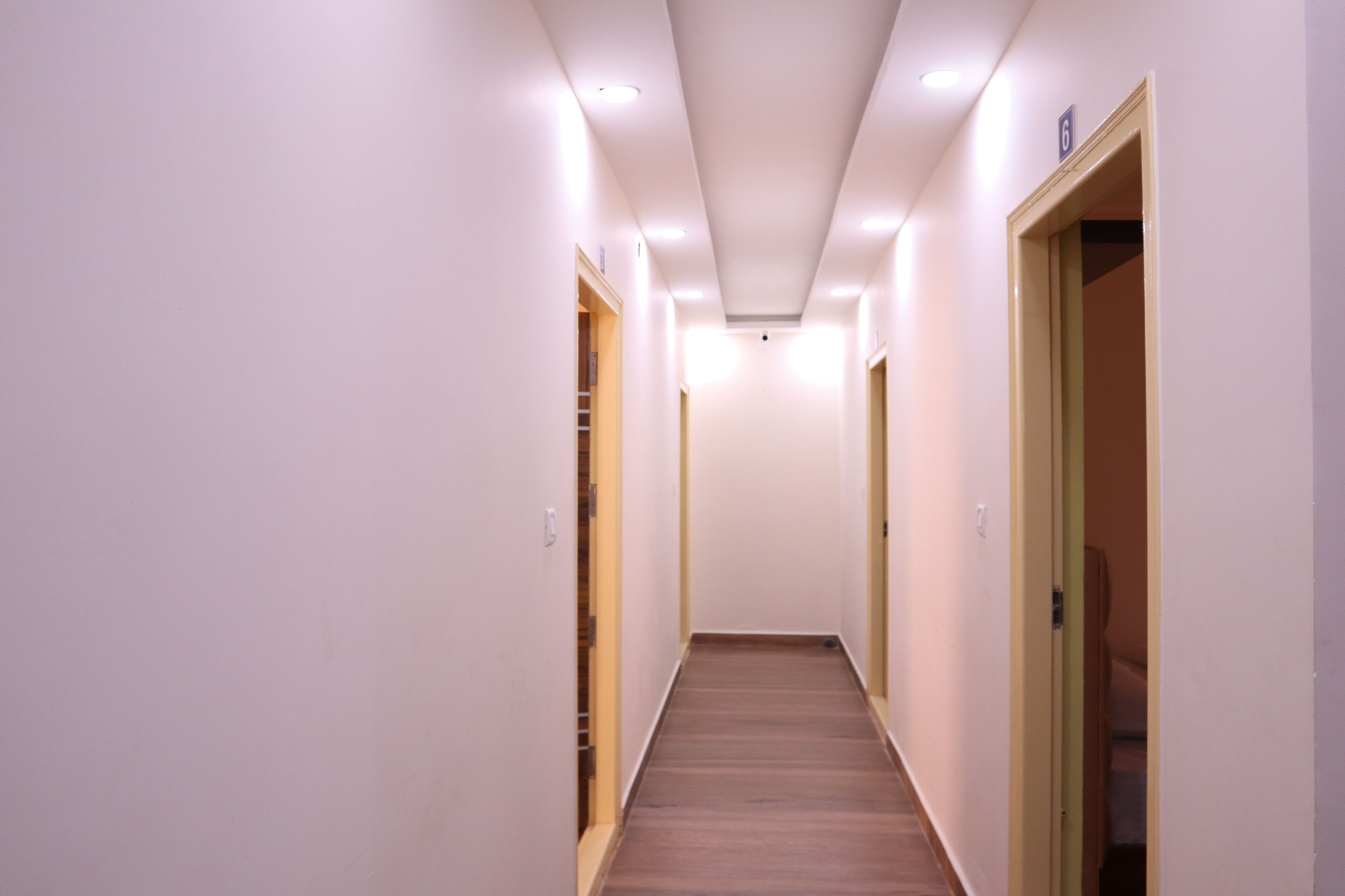A narrow, well-lit hallway with wooden flooring and white walls.
