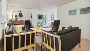 A modern living room with a sofa, chairs, a table, and a fireplace. - 3 bedroom nice home in Nexø (Nexø)