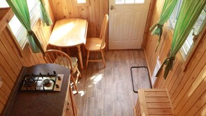 Interior de uma cabana de madeira com cozinha, sala de jantar e escada.