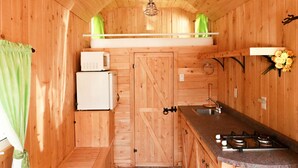 Uma cabana de madeira compacta com cozinha compacta, incluindo pia, fogão e micro-ondas.