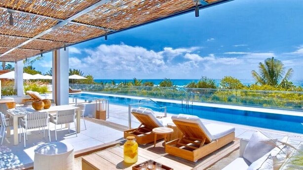 A poolside area with lounge chairs, a table with drinks, and a view of the ocean. - Romantic-Paradise-Luxurious-5 star-1BR-OceanFront-View-Balcony-Miami-South-Beach (Miami Beach)