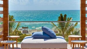 A balcony with a bed, two small tables, and a view of the ocean. - Romantic-Paradise-Luxurious-5 star-1BR-OceanFront-View-Balcony-Miami-South-Beach (Miami Beach)