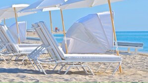 Beach chairs with white umbrellas, arranged on a sandy beach with the ocean in the background. - Romantic-Paradise-Luxurious-5 star-1BR-OceanFront-View-Balcony-Miami-South-Beach (Miami Beach)
