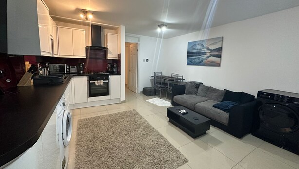A modern apartment with a kitchen, living room, and dining area. It includes a sofa, a coffee table, and a dining table. - Charming 1-bed Apartment in Chigwell (Chigwell)