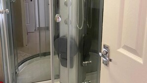 A glass-enclosed shower stall with a toilet and a glass shelf. - Charming 1-bed Apartment in Chigwell (Chigwell)