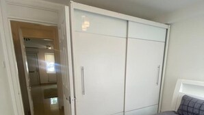 A bedroom with a bed, a wardrobe, and a bathroom visible through an open door. - Charming 1-bed Apartment in Chigwell (Chigwell)