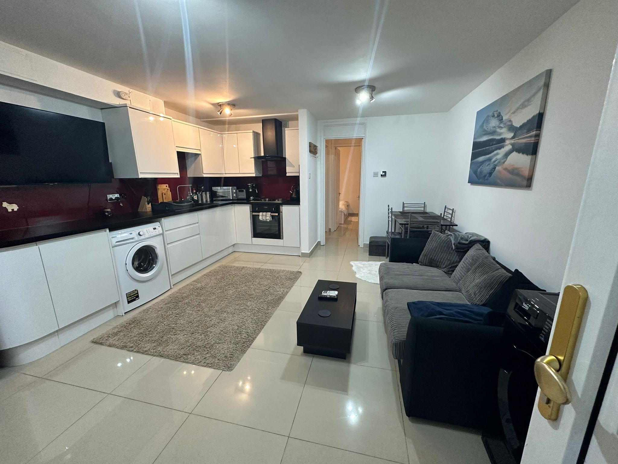Un apartamento moderno con cocina, comedor y sala de estar. Cuenta con lavadora, mesa de comedor y sofá.