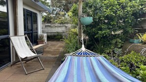 A hammock in a garden area with a chair and a hanging pot. - Comfortable family home, Privacy & convenience, pets welcome! (Papamoa)