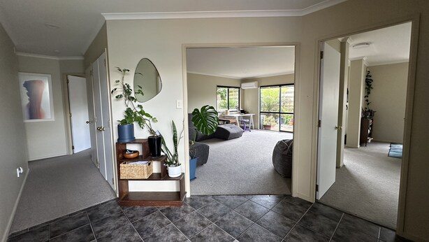 A spacious living area with a large window, a sofa, and a coffee table. - Comfortable family home, Privacy & convenience, pets welcome! (Papamoa)