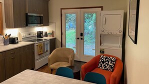 A compact kitchen with a microwave, stove, and toaster, a dining area with a table and chairs, and a laundry area with a washing machine.