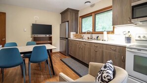 A compact kitchen with a dining area, wooden cabinets, a microwave, and a stove.