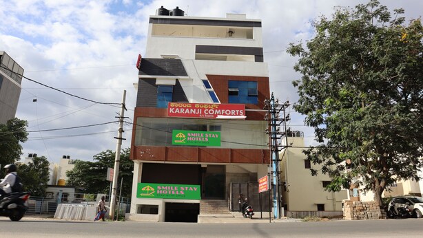 A multi-story building with signage for Karanji Comforts and Smile Stay Hotels. - Smile stay Karanji Comforts (Bengaluru)