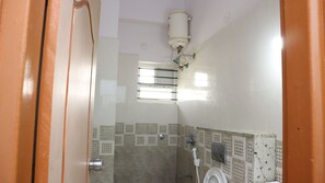 A bathroom with a shower, a toilet, and a water heater mounted on the wall. - Smile stay Karanji Comforts (Bengaluru)