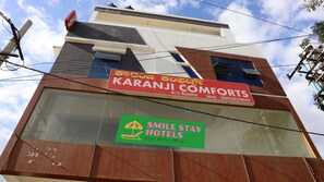 A building with signs for Karanji Comforts and Smile Stay Hotels. - Smile stay Karanji Comforts (Bengaluru)