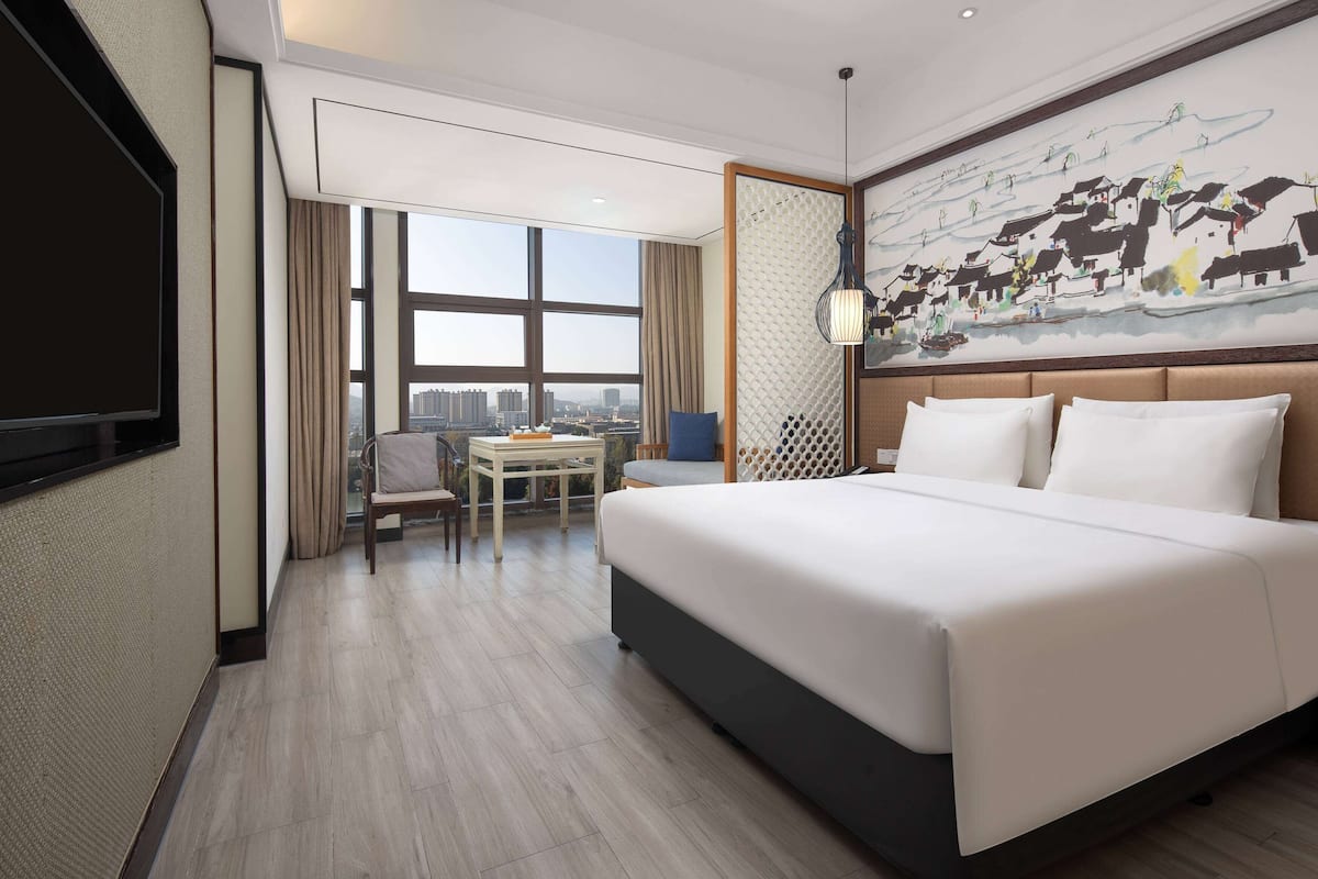 A hotel room with a large bed, a desk, and a view of the city.