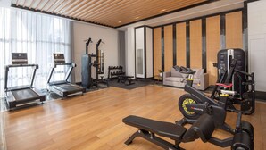 Une salle de sport équipée de tapis de course, d’haltères, d’un banc de développé couché et d’un vélo d’appartement.