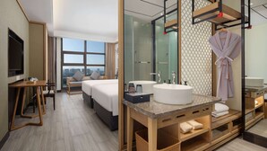 Une chambre d’hôtel moderne dotée d’un grand lit, d’un coin salon, d’une salle de bain avec un grand miroir et offrant une vue sur la ville.