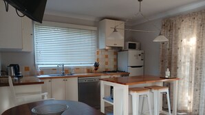 Una cocina compacta con una isla de madera, armarios blancos, lavavajillas y microondas.