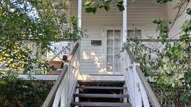 Una escalera de madera que conduce a una casa blanca con una ventana y una puerta.