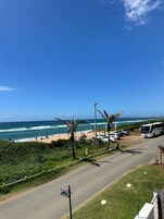 Una carretera costera con playa, palmeras y un autobús.