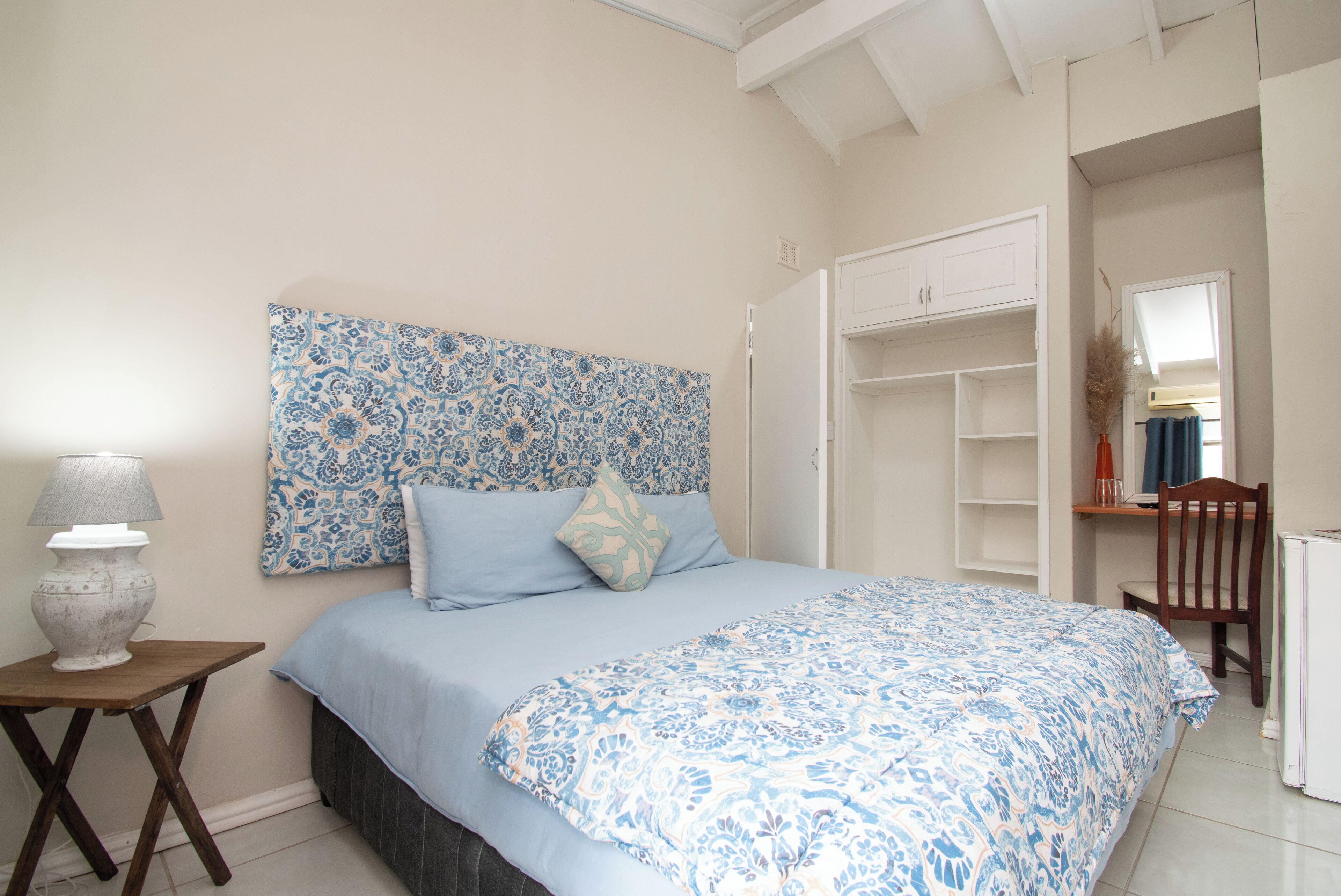 Une chambre à coucher comprenant un lit, une table de chevet, une chaise et une armoire.