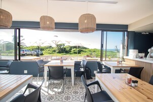 Un restaurante con terraza, grandes ventanales y vista al océano.