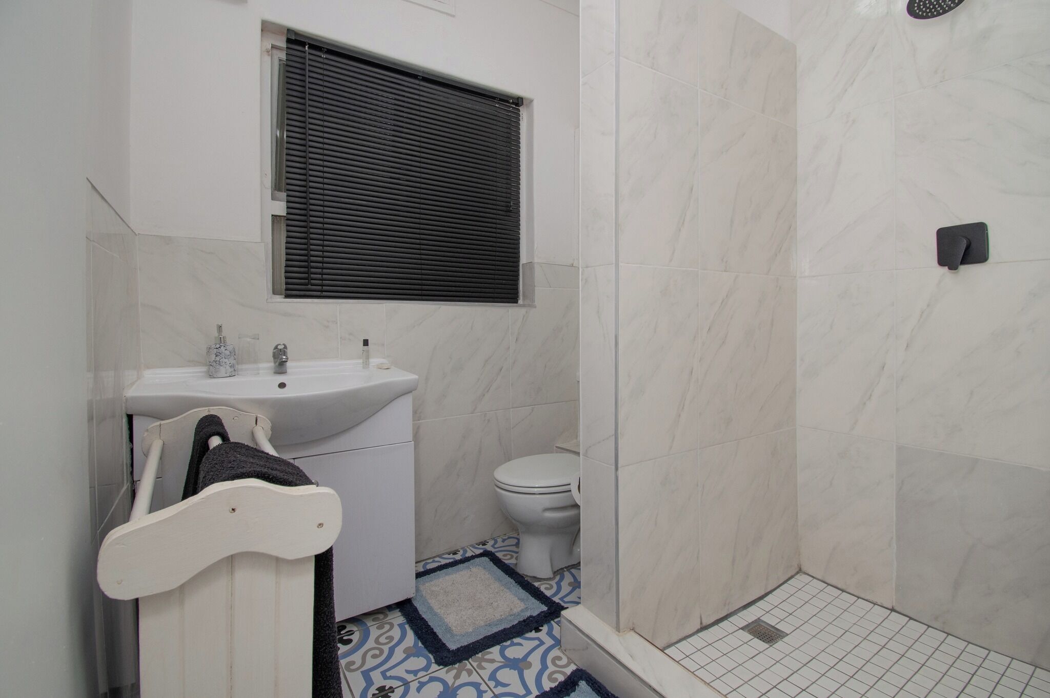 Un baño con lavamanos blanco, inodoro y zona de ducha.