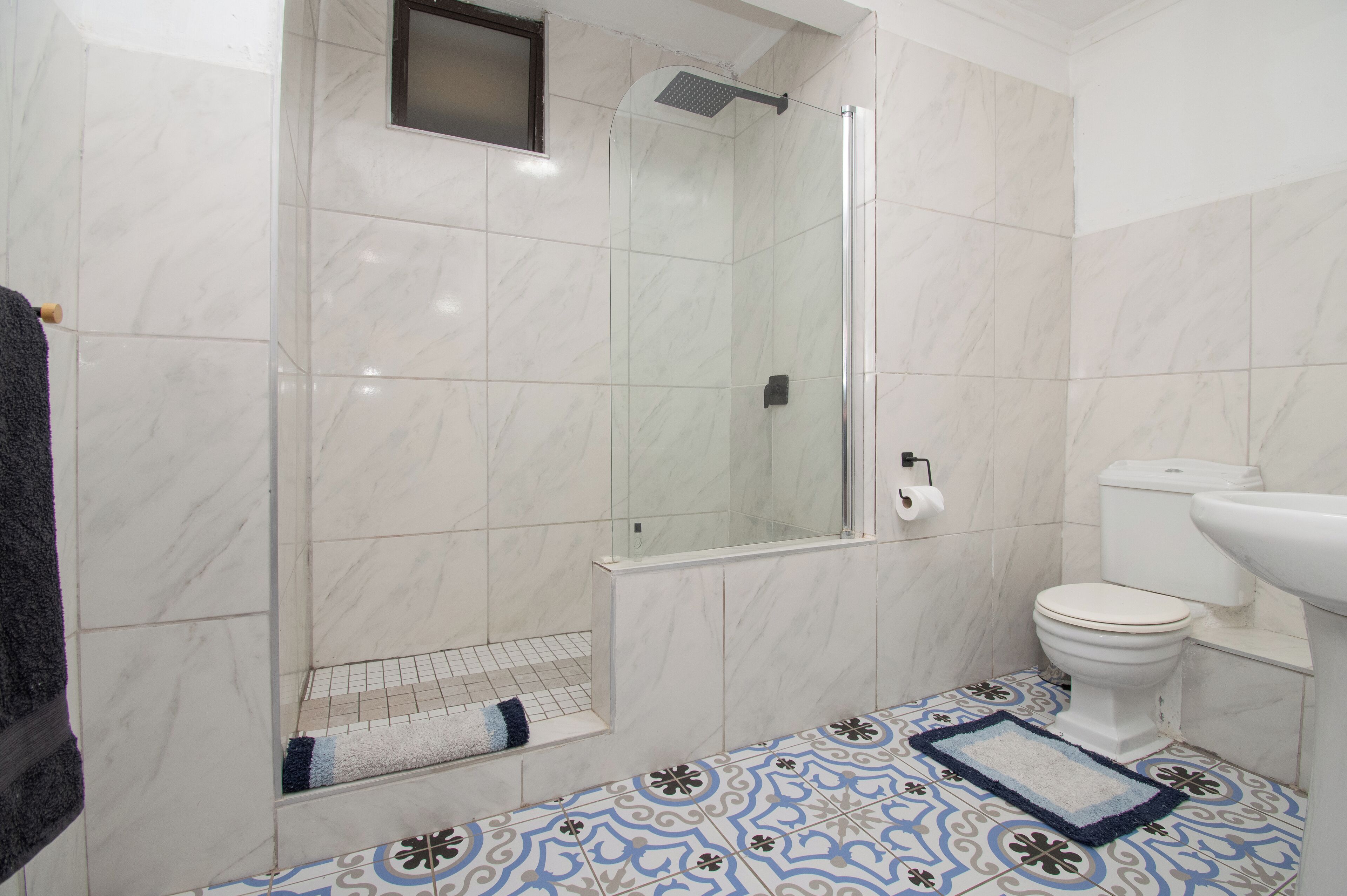 Un baño con ducha de mampara, inodoro y lavamanos.