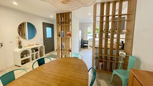 A modern dining area with a wooden table, teal chairs, a round mirror, and a decorative ceiling light. - Modern House Near Beach: 4 Bedrooms, Full Kitchen, WiFi, Terrace, Parking (Bretignolles-sur-Mer)