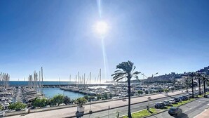 Un porto turistico con barche, cielo sereno e una strada con auto.