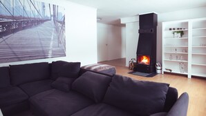 A modern living room with a sectional sofa, a fireplace, and a bookshelf.