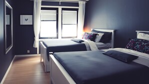 A bedroom with two beds, a window with blinds, and a framed picture on the wall.