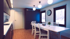 A modern kitchen with a white countertop, wooden cabinets, and a dining area with a white table and chairs.