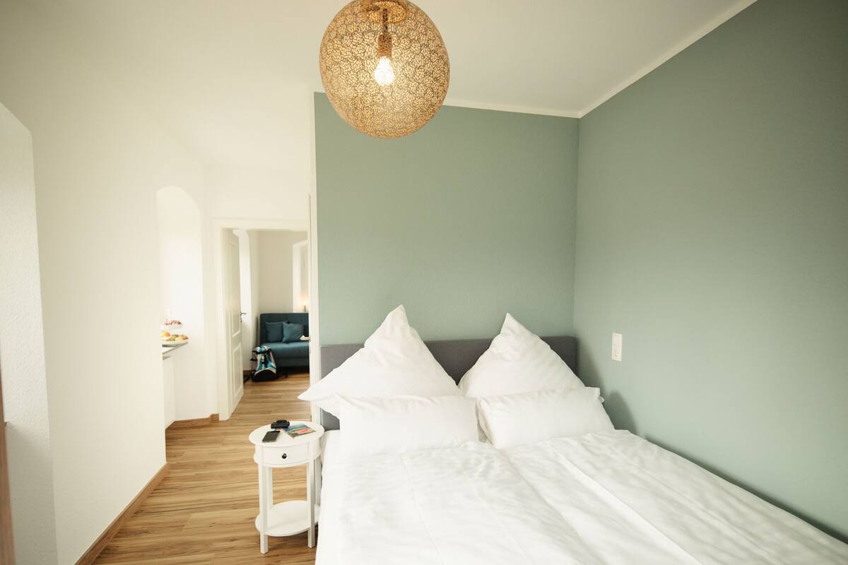 Ein Schlafzimmer mit Bett, Nachttisch und einer Pendelleuchte.