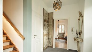 Una escalera con escalones de madera que lleva a una puerta blanca, una alfombra gris y un espejo decorativo en la pared.