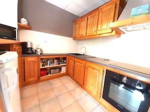 A compact kitchen with wooden cabinets, a built-in oven, a coffee maker, and a toaster. - Charming 3-Bedroom Souplex Apt for 7 with Terrace - Vignec, France (Vignec)