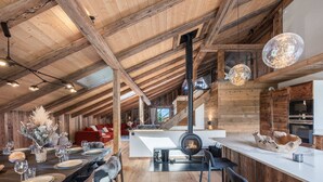 Ein geräumiger Loft mit freiliegenden Holzbalken, einem zentralen Kamin und einer modernen Küche.