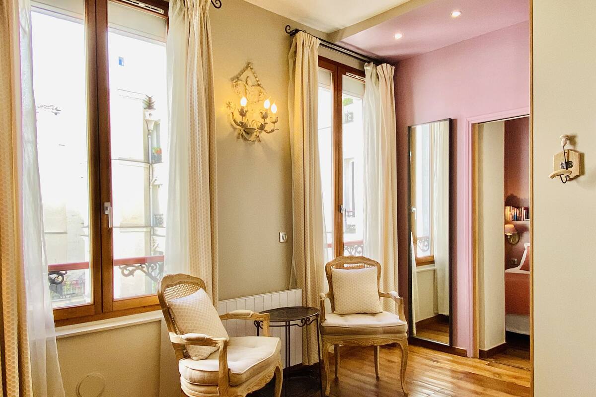 Une pièce comprenant deux fauteuils rembourrés, une petite table et un lustre.